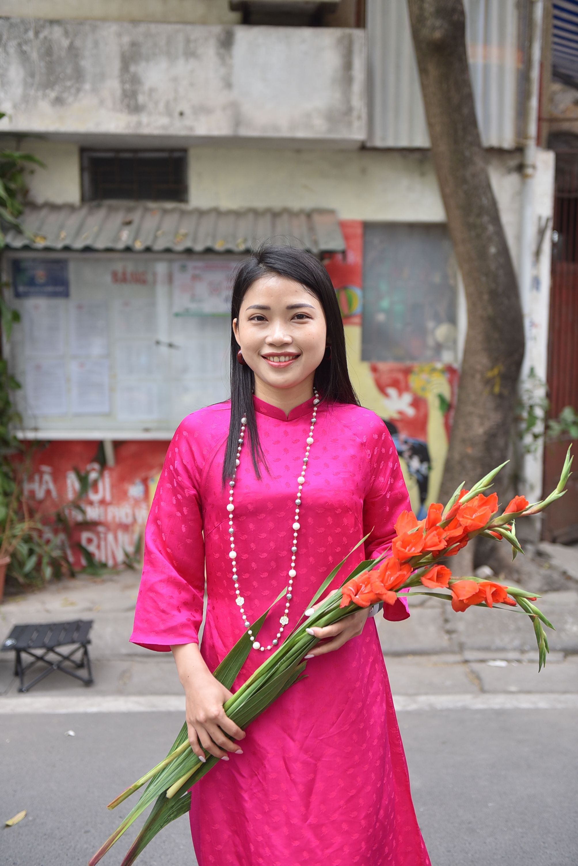 Smiling Woman in Traditional Pink Dress Holding Flowers · Free Stock Photo