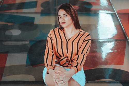Gratis Foto Wanita Dengan Blus Oranye Dan Hitam Serta Pose Rok Putih Foto Stok