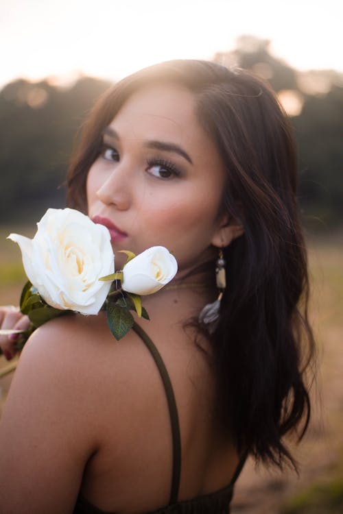 Selective Focus Photo of Woman Posing While Holding White Rose Flowers