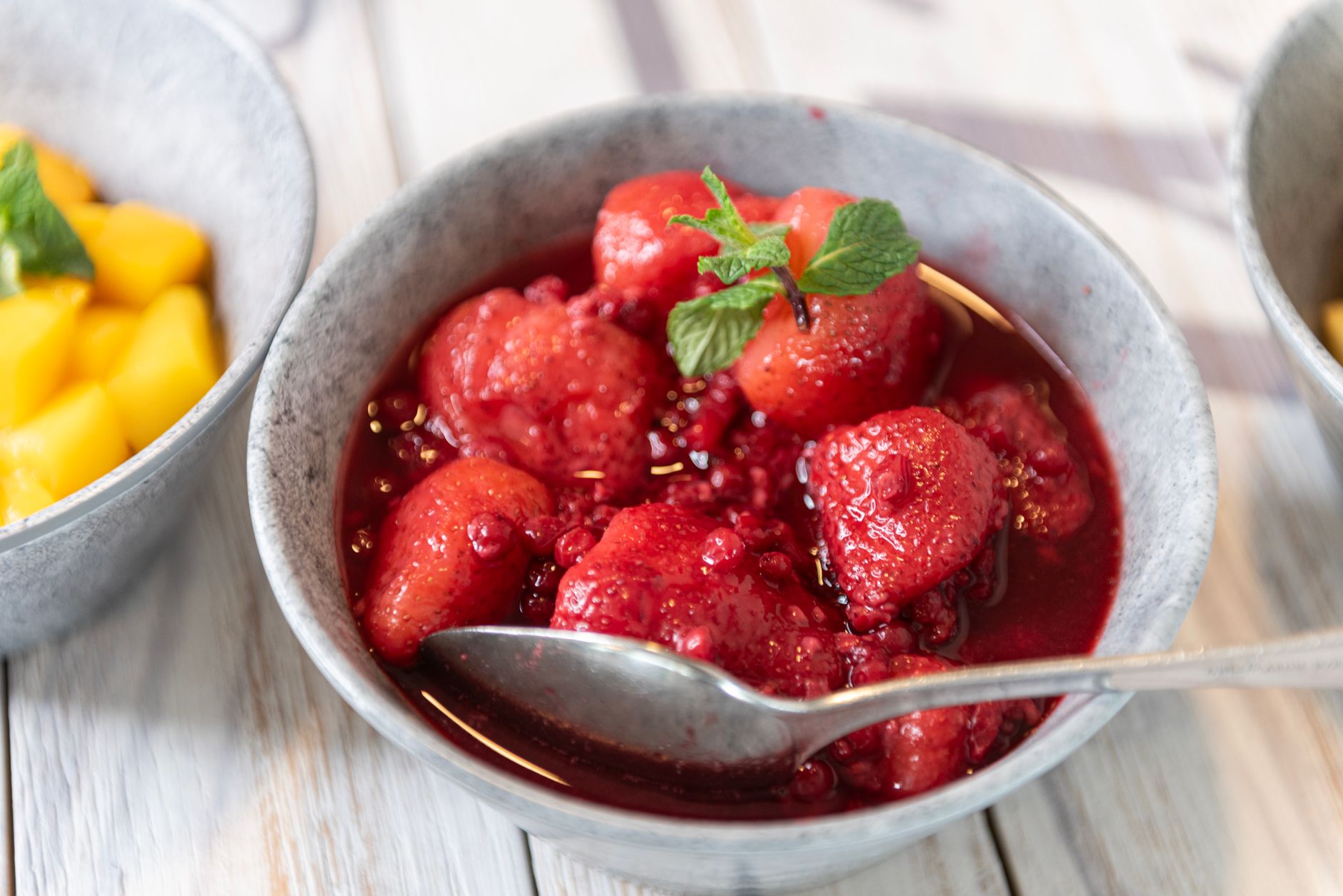 The Ultimate Strawberry Chiffon Shortcake Recipe Bowl of fresh strawberries in a luscious syrup, garnished with mint leaves.