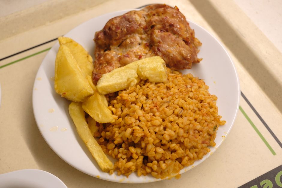 A 'Plato del Día' lunch plate from a local 'comedor' in the Dominican Republic, featuring rice, beans, and stewed meat.