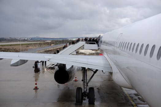 A side view of passengers boarding a large airplane at an airport on an overcast day.