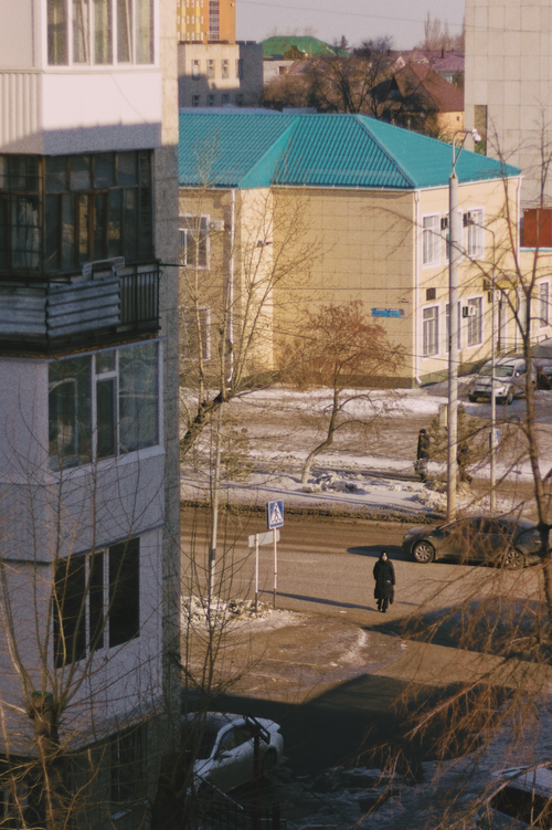 Free A city street in winter with a solitary person crossing and snow on the ground. Stock Photo