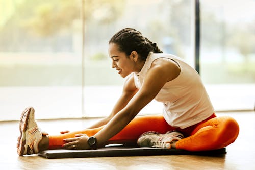 Free Woman Stretching on Ground Stock Photo