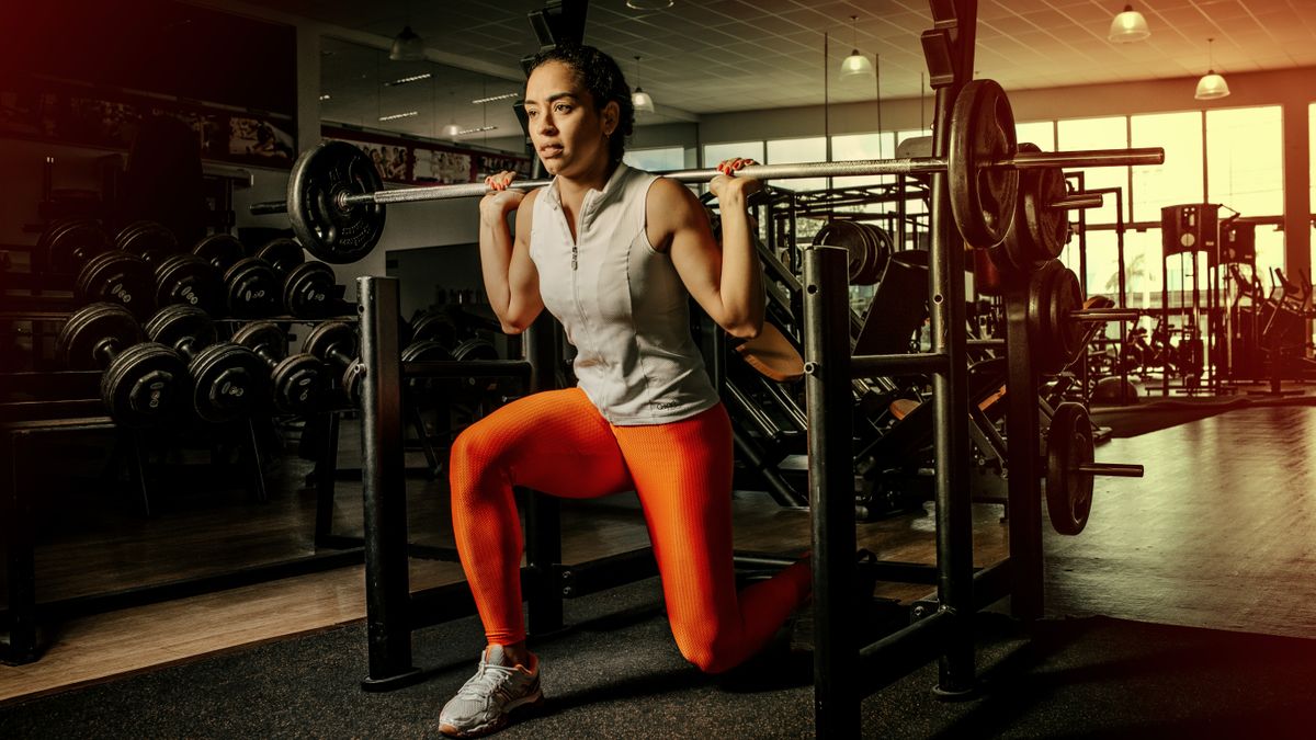 Confident woman lifting weights in a modern gym, showcasing strength and fitness.