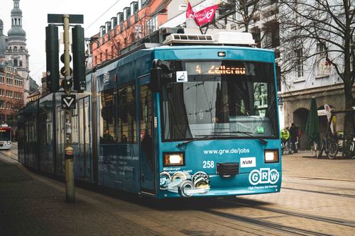 Free Blue tram on a city street with historic European architecture, capturing urban transport. Stock Photo
