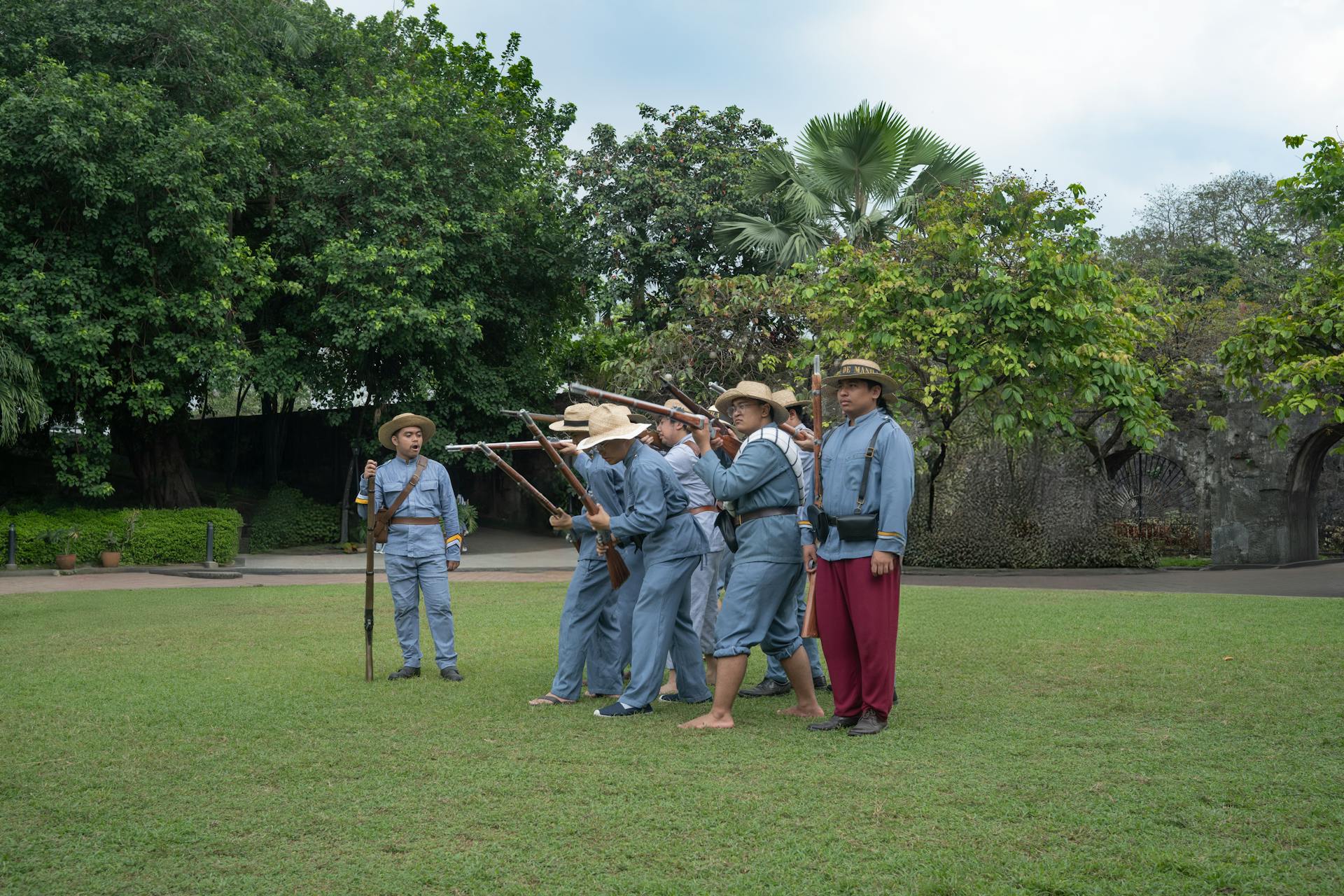 Actors in period costumes reenacting a historical scene in a lush Manila park.