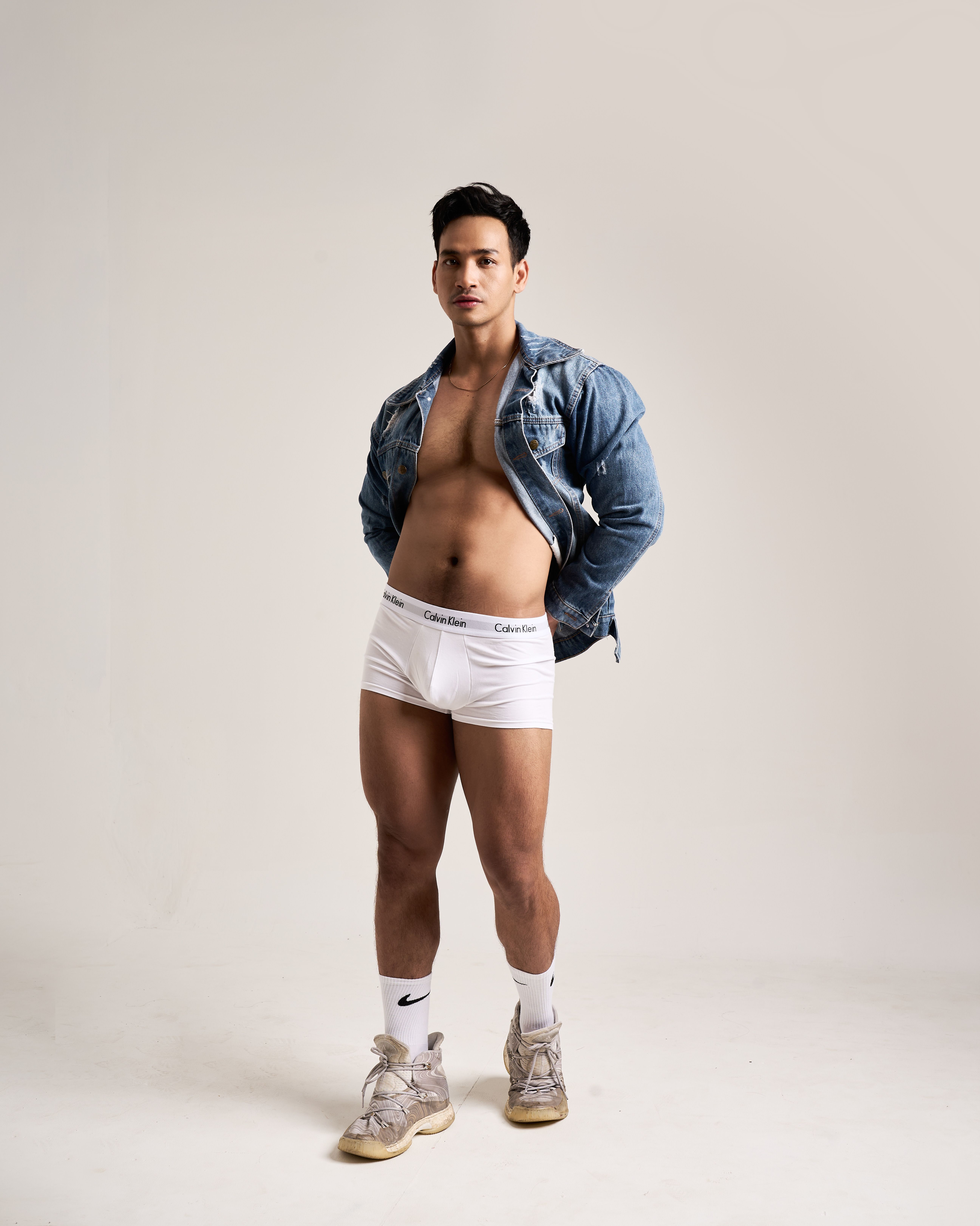 Fashionable male model posing in studio with denim jacket and white underwear