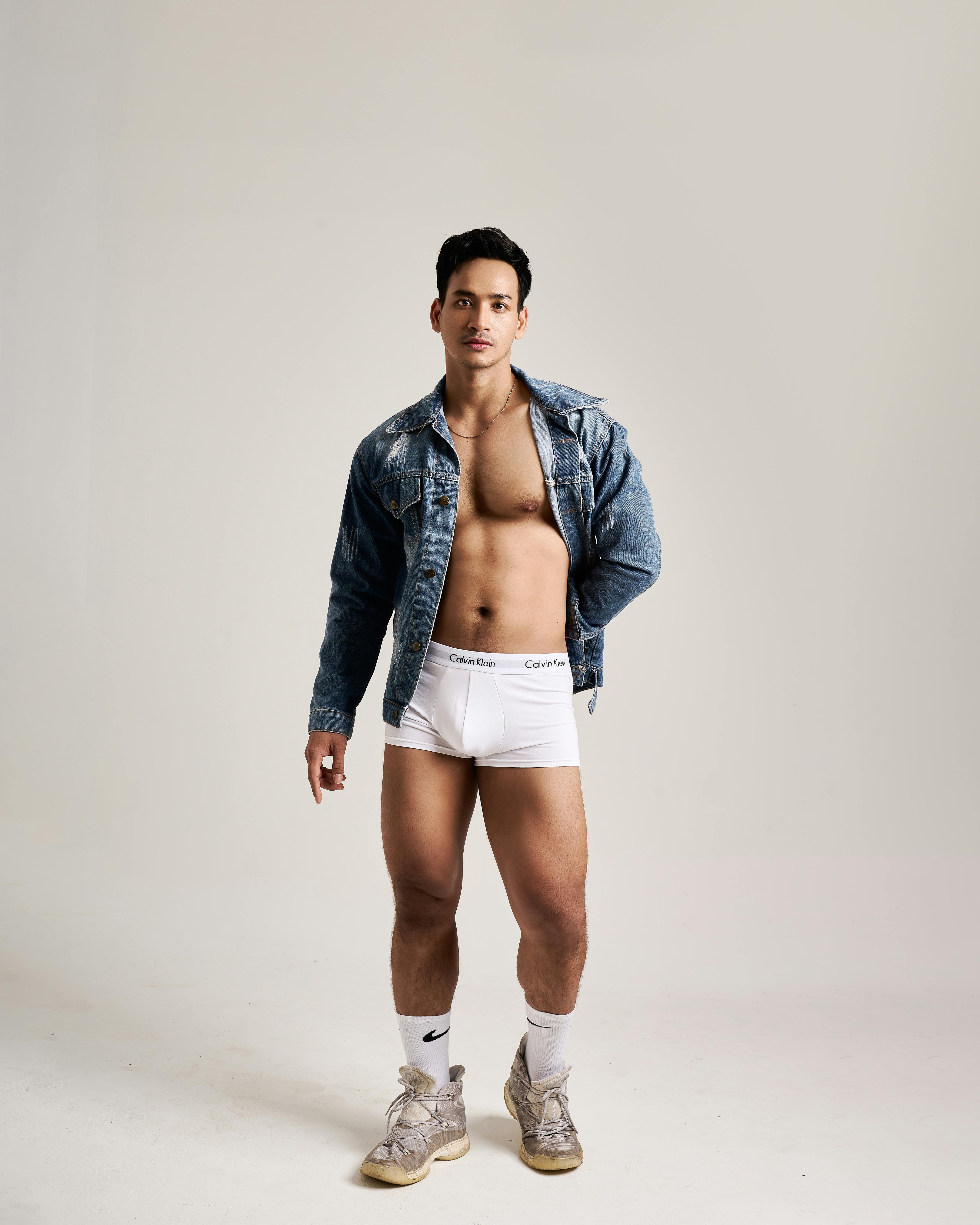 Gratis Modelo masculino de moda posando con chaqueta vaquera y ropa interior en un estudio. Foto de stock