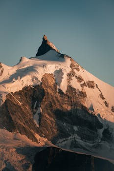 Stunning view of a snow-covered alpine peak in the Swiss Alps at sunrise.