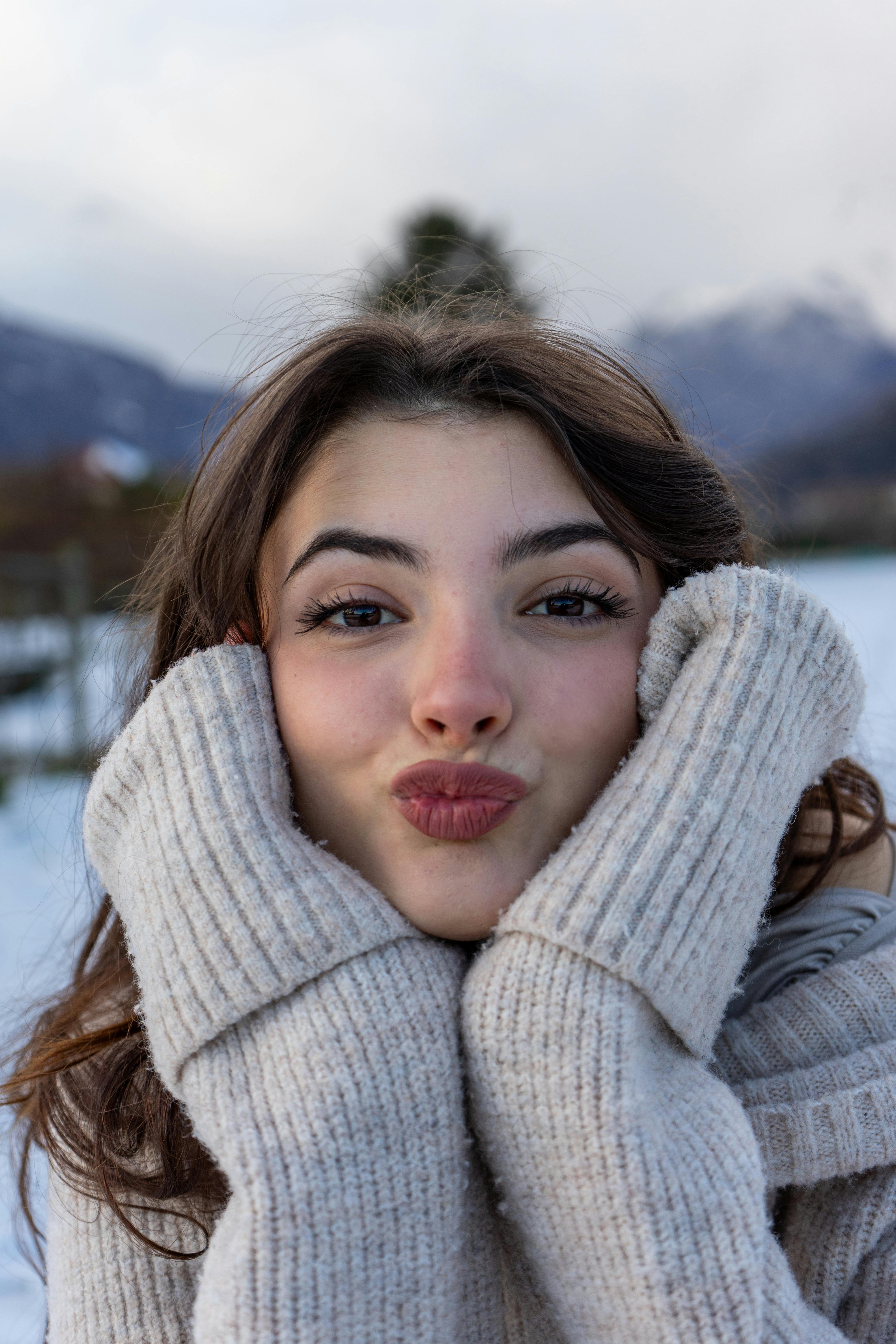 Young woman enjoying snowy winter day in Italian landscape, cozy in a sweater.