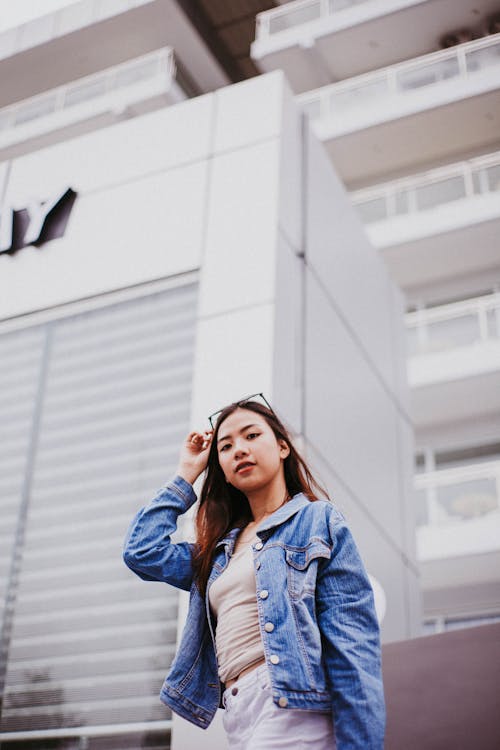 Foto De Mulher Com Jaqueta Jeans Azul Posando Com Um Prédio Ao Fundo