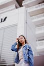 自信的年轻女性穿着休闲牛仔夹克，在现代建筑背景下摆姿势