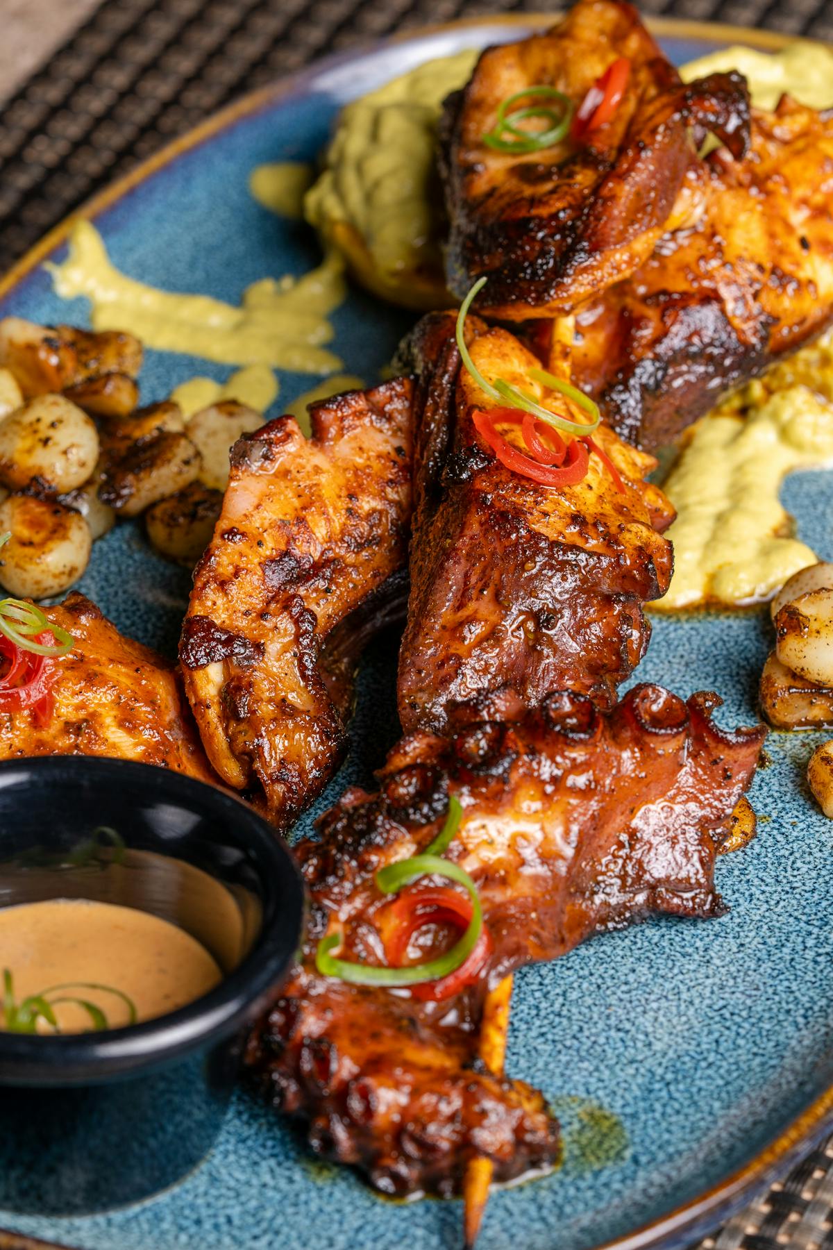 Grilled chicken skewers on a plate with vegetables and dipping sauce