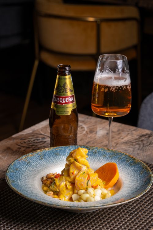 Free Traditional Peruvian ceviche served with Cusqueña beer on a rustic table. Stock Photo