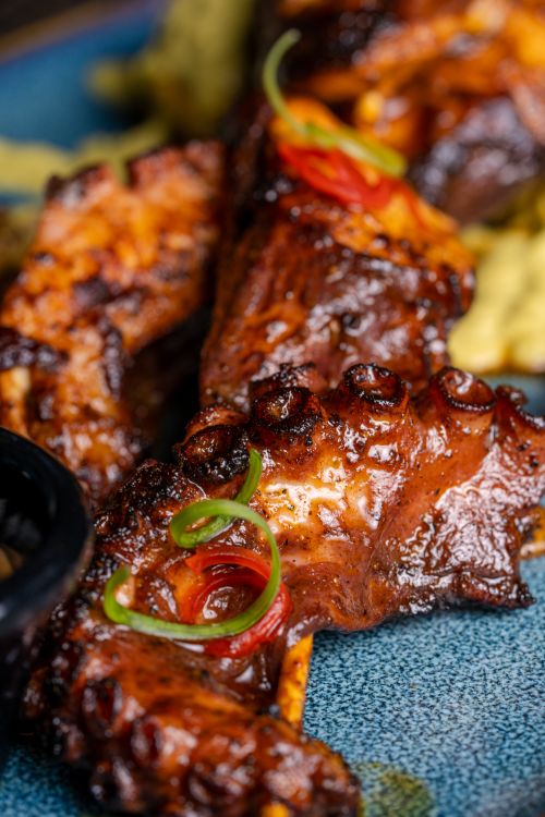 Free Delicious grilled octopus served on a blue plate with fresh garnish. Stock Photo