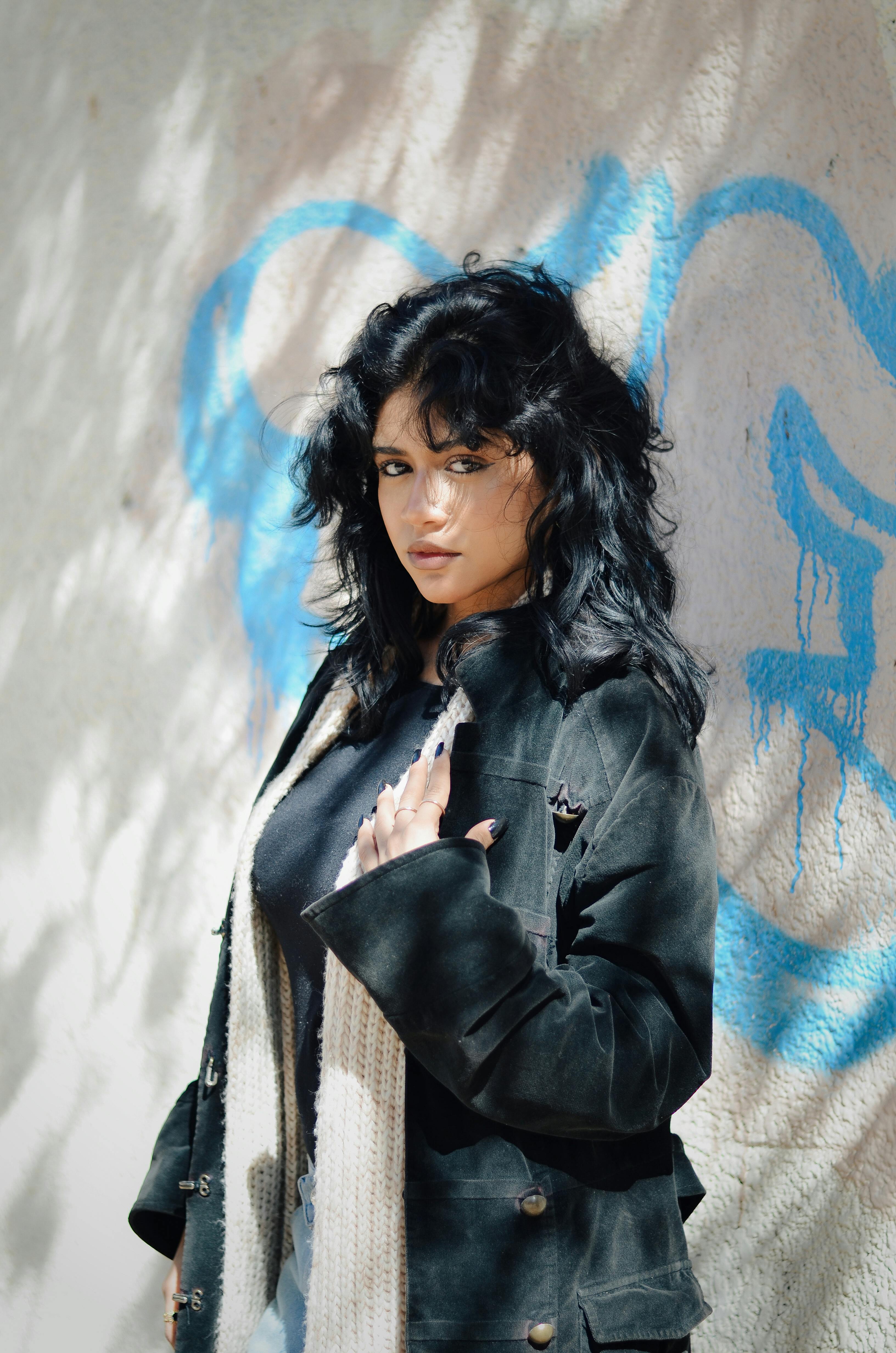 Chic female model poses against vibrant graffiti wall in Cairo, Egypt.