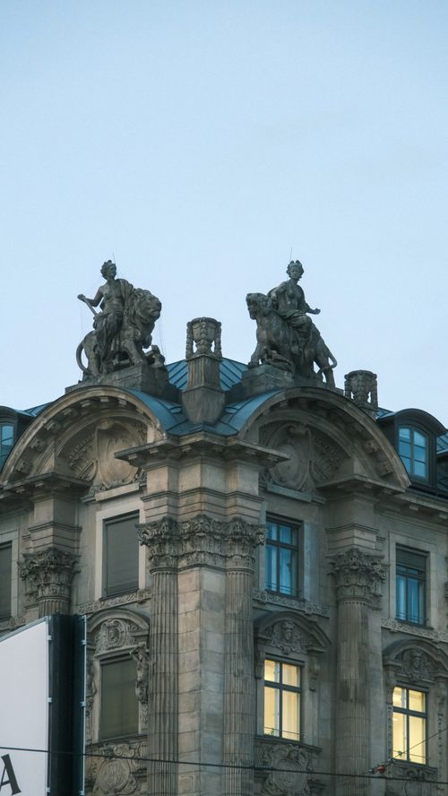 Free Classic ornate European building with intricate statues on rooftop at twilight. Stock Photo