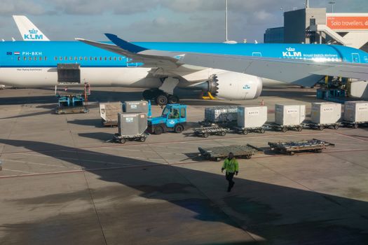 KLM aircraft preparing for departure on a sunny day with ground crew assisting.