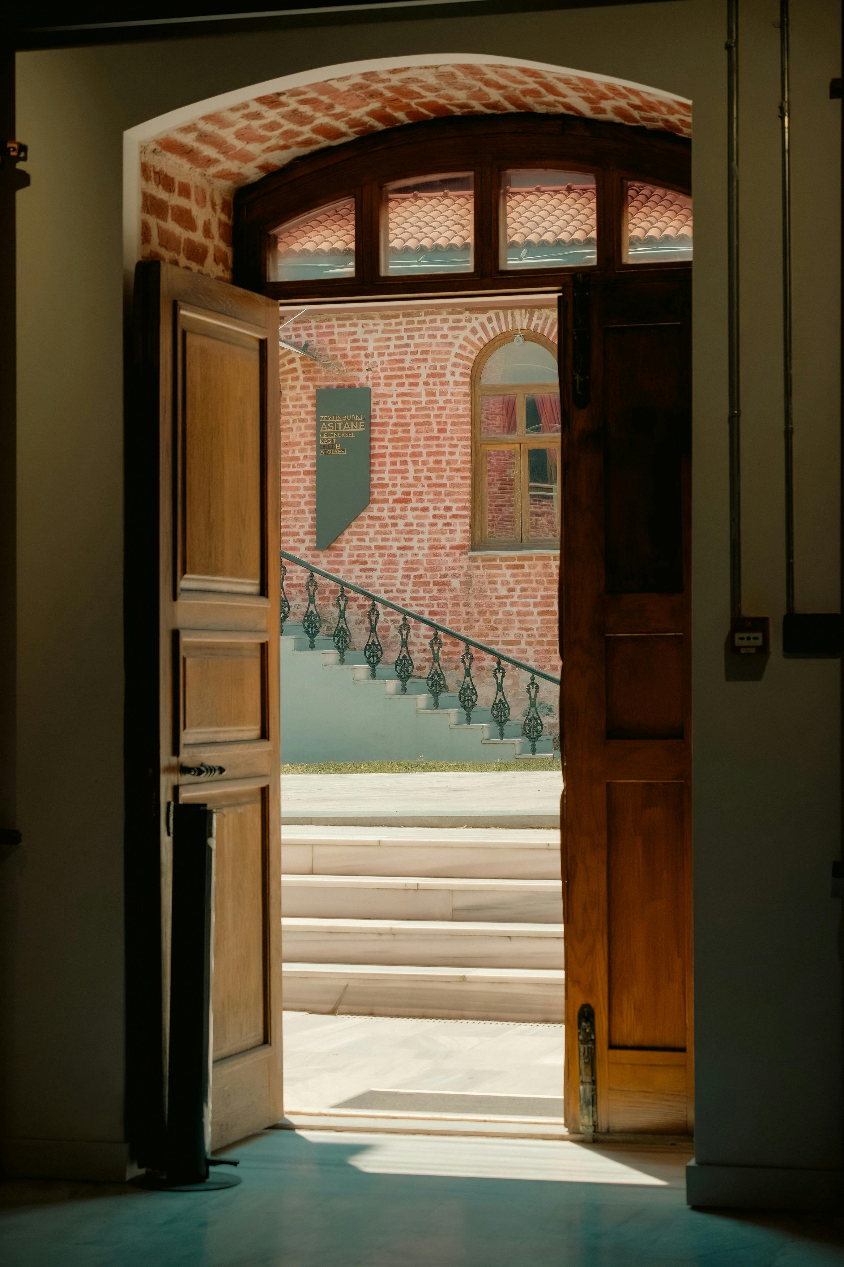 Gratis Una porta di legno si apre per rivelare un rustico edificio in mattoni con gradini. Caldo e invitante. Foto a disposizione