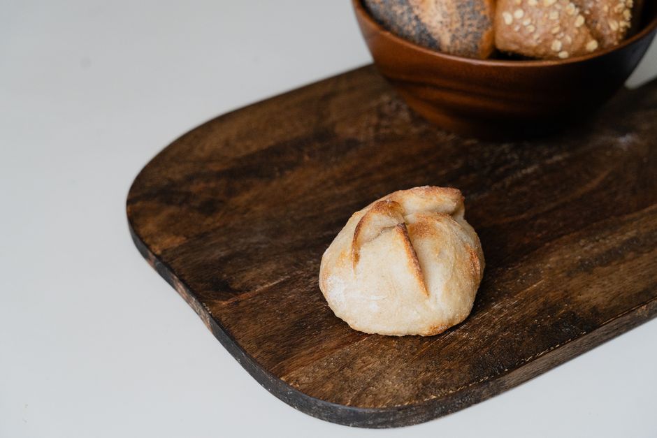 Several round kaiser rolls with their signature five-pointed pinwheel crust, split open to show a chewy, open crumb.