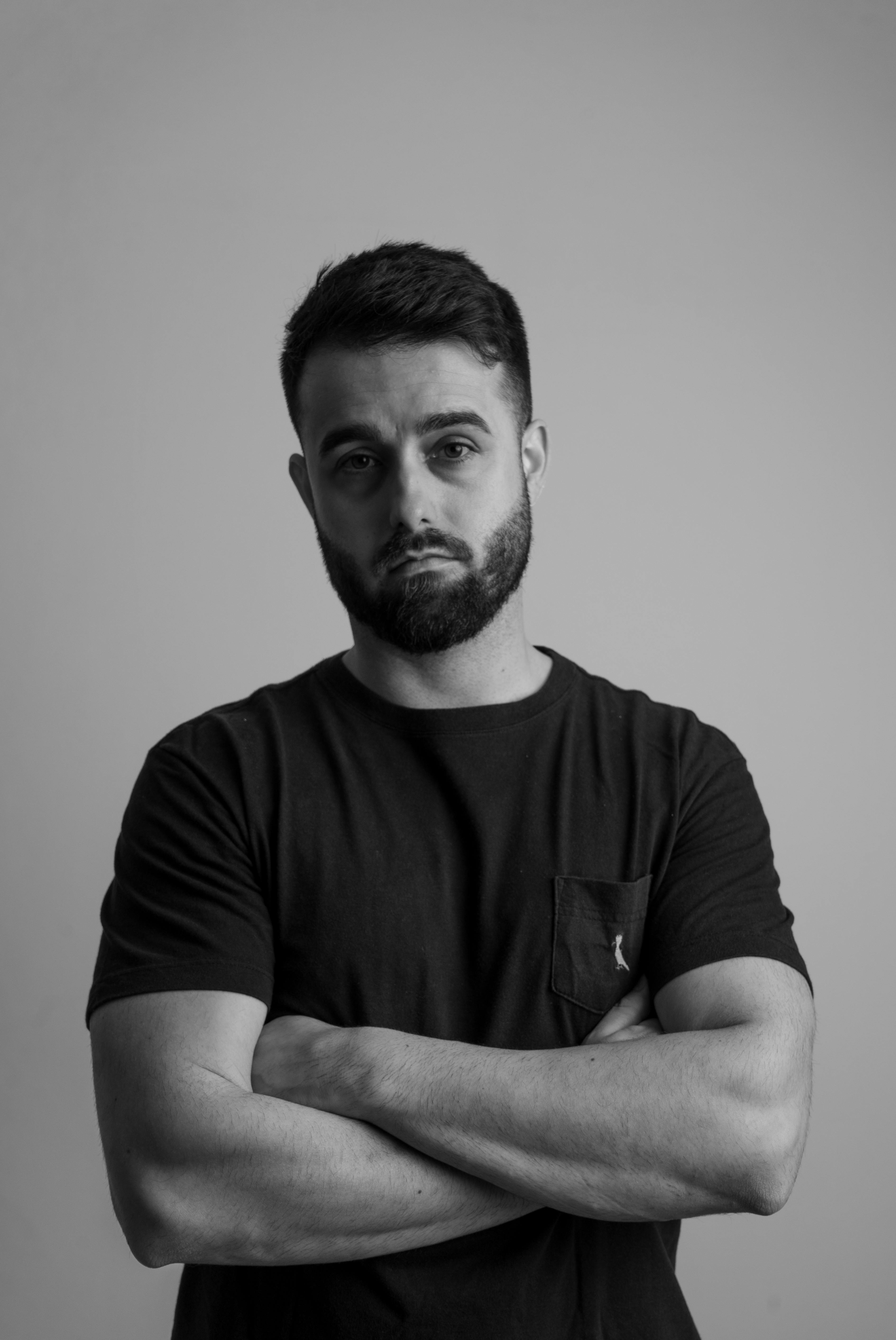 Black and white portrait of a confident man with a serious expression in studio lighting.