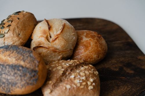 Free Close-up of assorted artisanal bread rolls on a wooden board showcasing texture and grains. Stock Photo