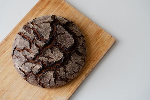A rustic round loaf of artisan bread with cracked crust on a wooden cutting board.