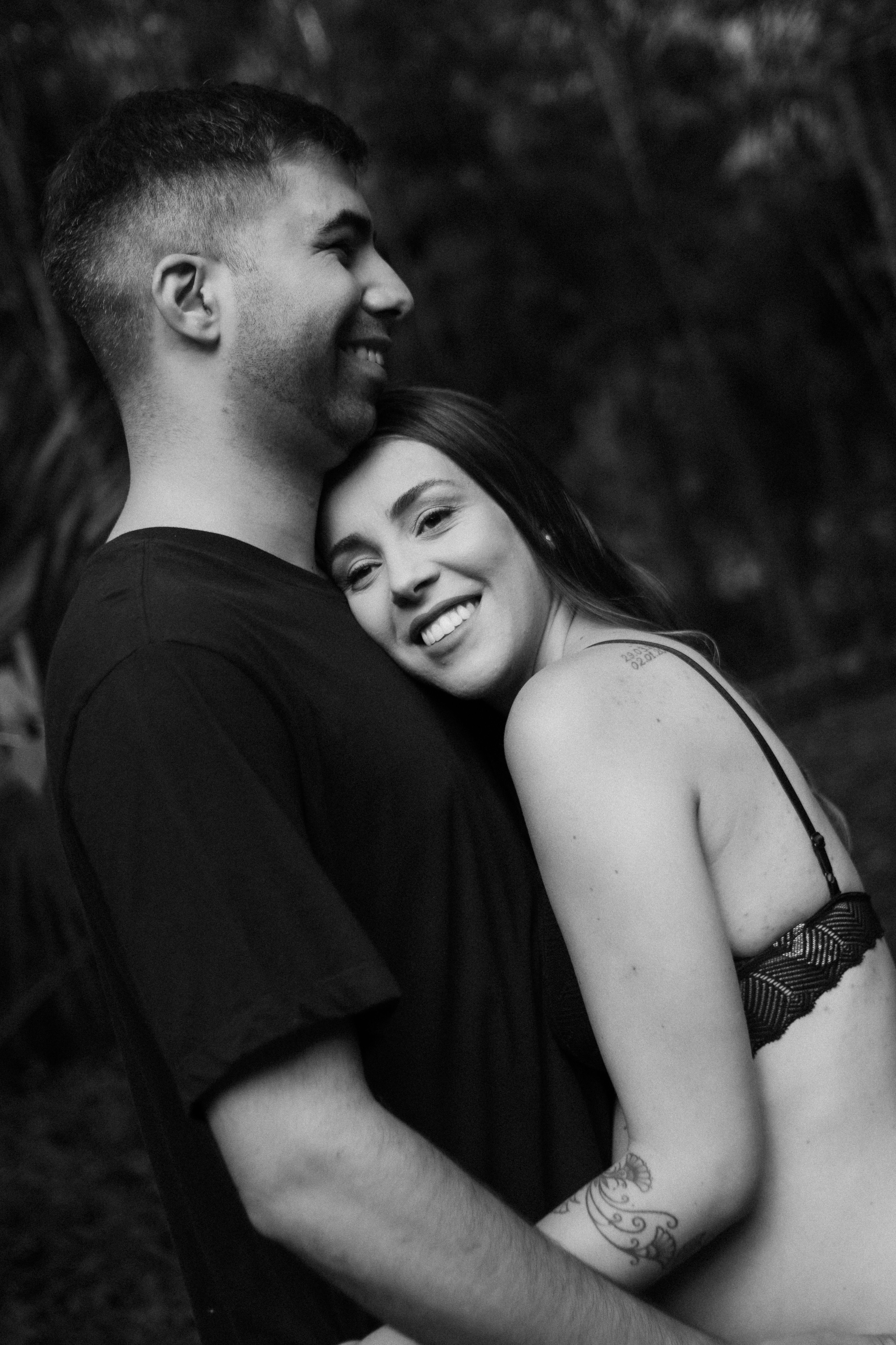 A romantic black and white image of a couple embracing outdoors.