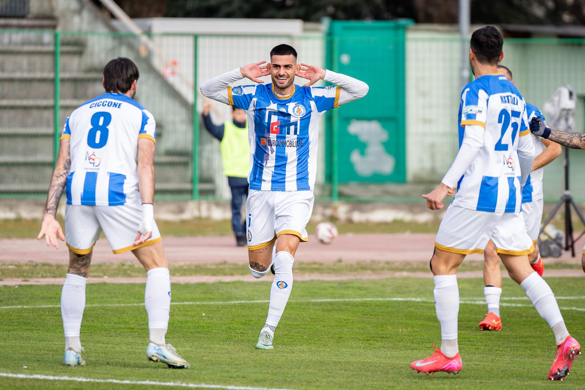Excited soccer players celebrating a goal on an outdoor field during a match.