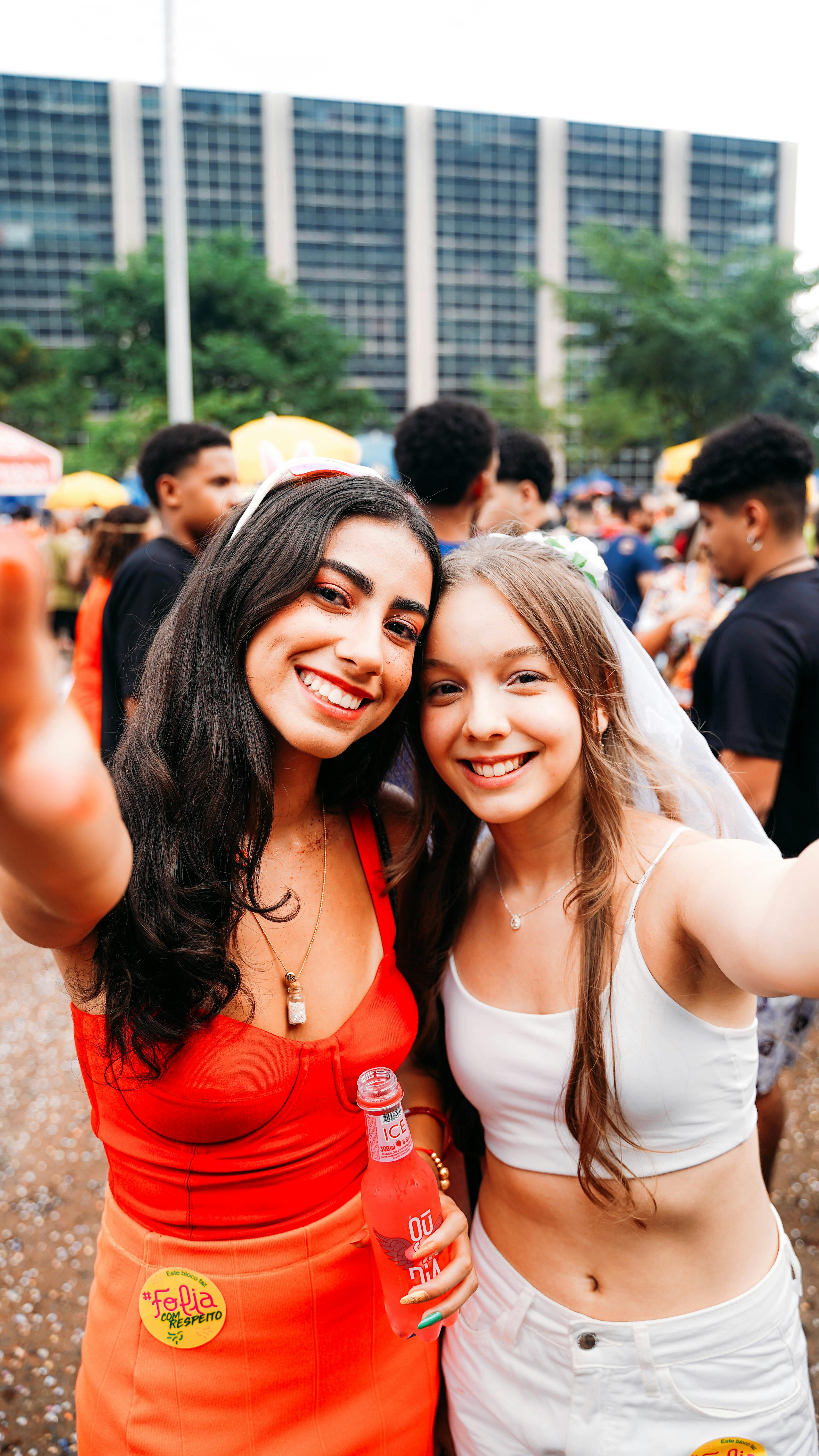 Two young women taking a selfie at an outdoor festival. Vibrant and joyful atmosphere.
