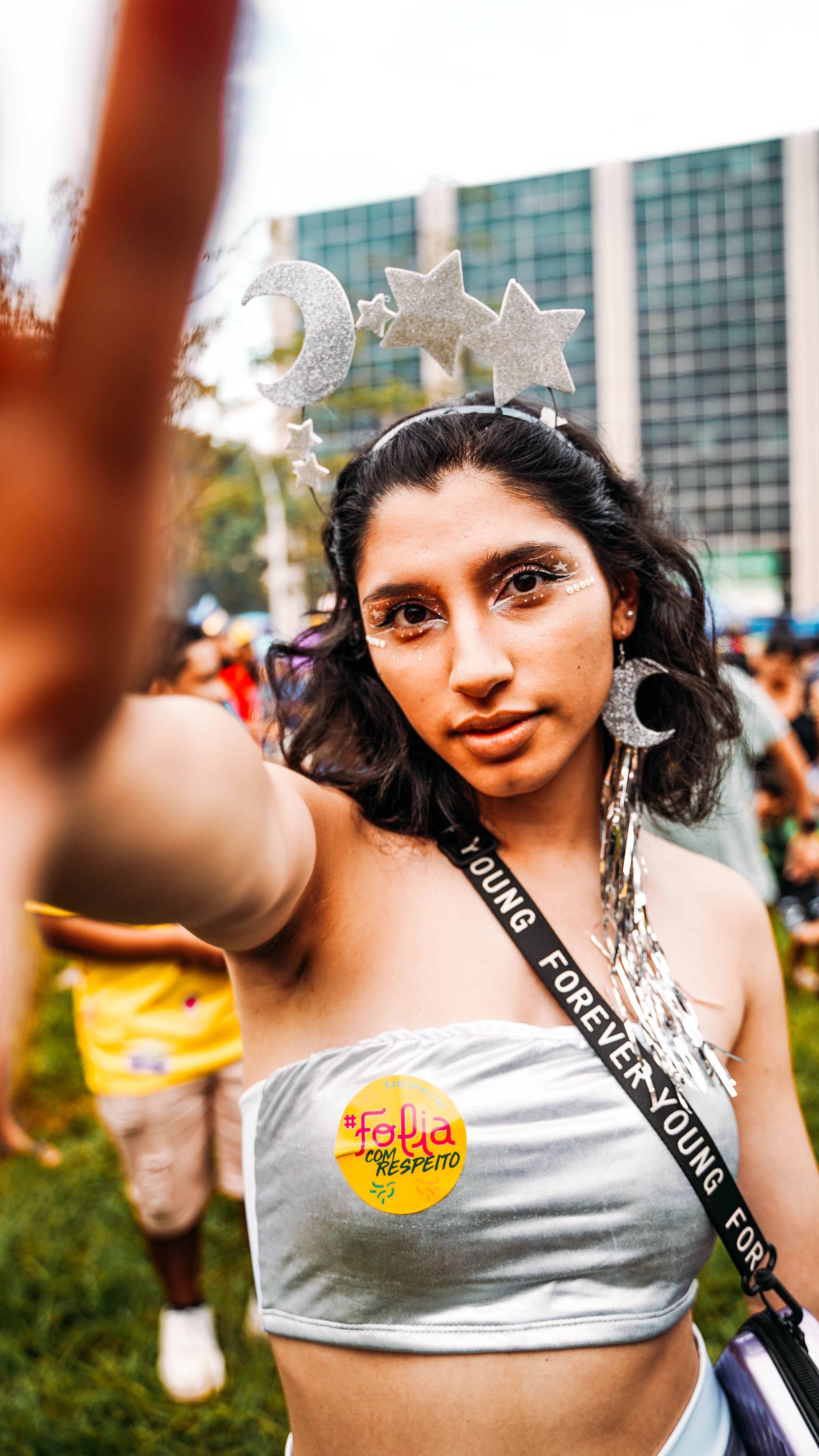 Young woman in costume at an outdoor festival, wearing a lunar headband and shimmering makeup.