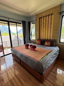 Spacious hotel room with mountain view, wooden floors, elegant decor, and natural light.