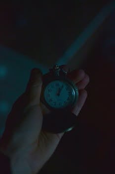 A nostalgic vintage pocket watch held in hand, showcasing time in a moody dim setting.