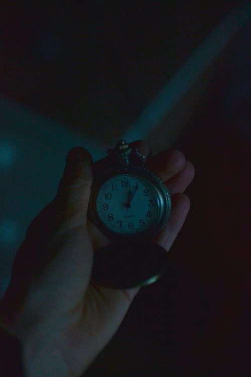 Free A nostalgic vintage pocket watch held in hand, showcasing time in a moody dim setting. Stock Photo