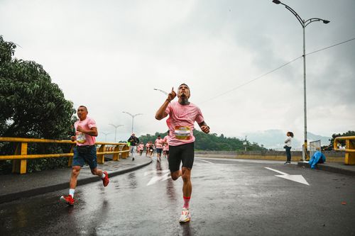 Free Runners participate in a competitive race on a wet city street wearing pink shirts. Stock Photo