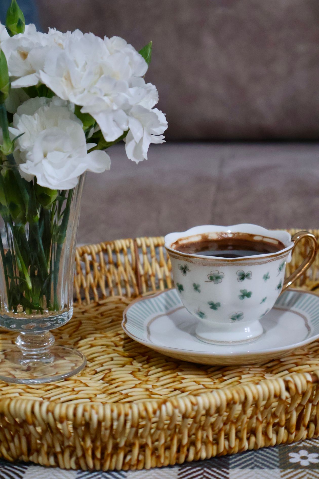 how to style a coffee table tray: a teacup and saucer with white flowers on a woven tray