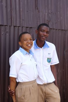 Two students in uniform posing outdoors on a sunny day, expressing joy and togetherness.