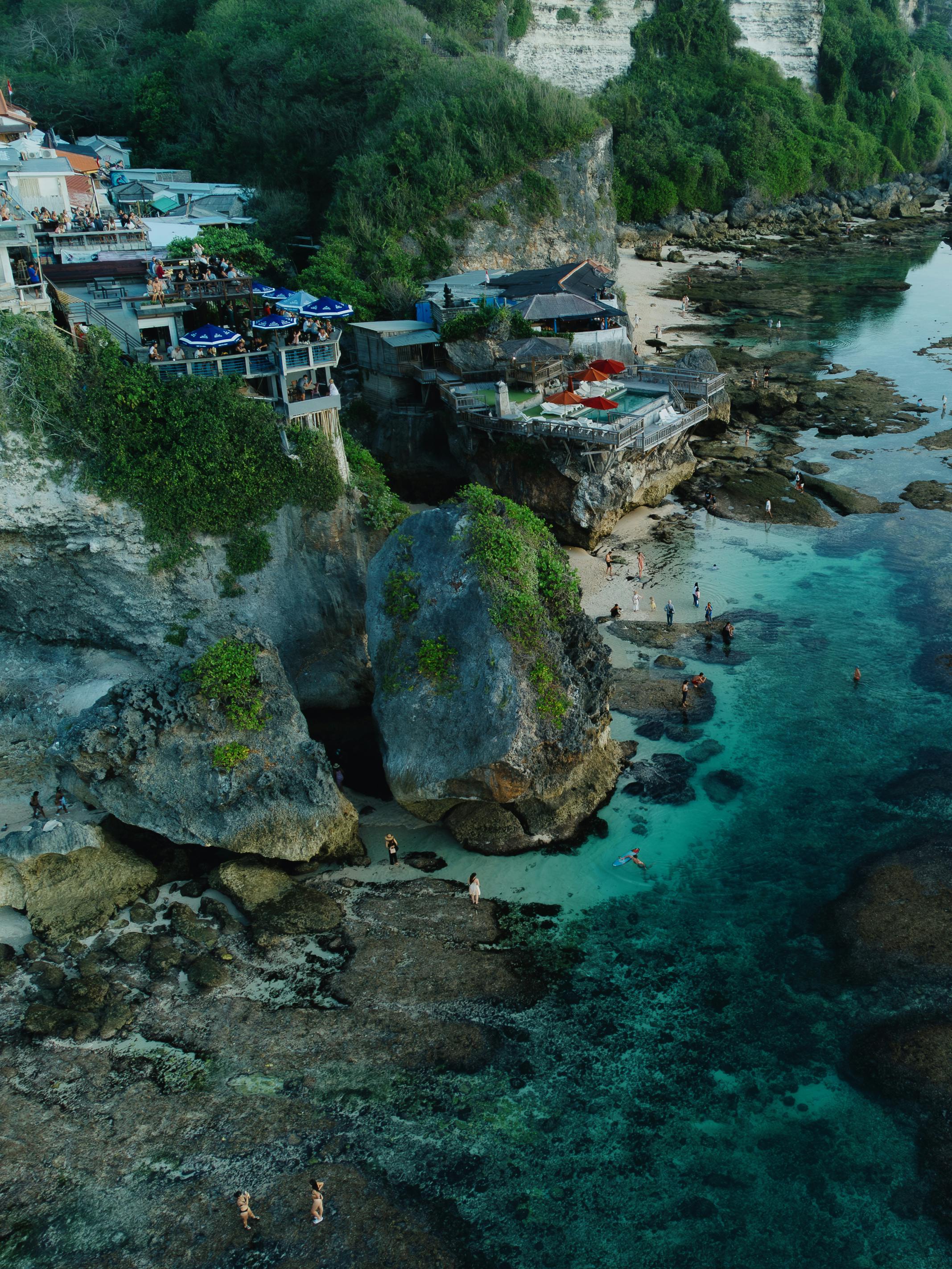 A breathtaking aerial shot of a secluded beach in Bali, featuring turquoise waters and rocky cliffs.