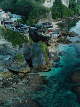 A breathtaking aerial shot of a secluded beach in Bali, featuring turquoise waters and rocky cliffs.