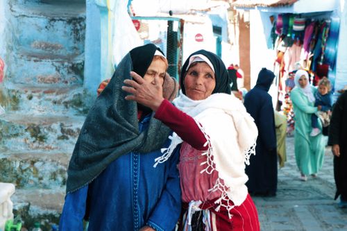 Free Two elderly women converse in colorful Moroccan street wearing traditional attire. Stock Photo