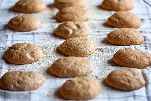 Free Golden brown freshly baked whole wheat bread rolls cooling on a linen cloth. Stock Photo
