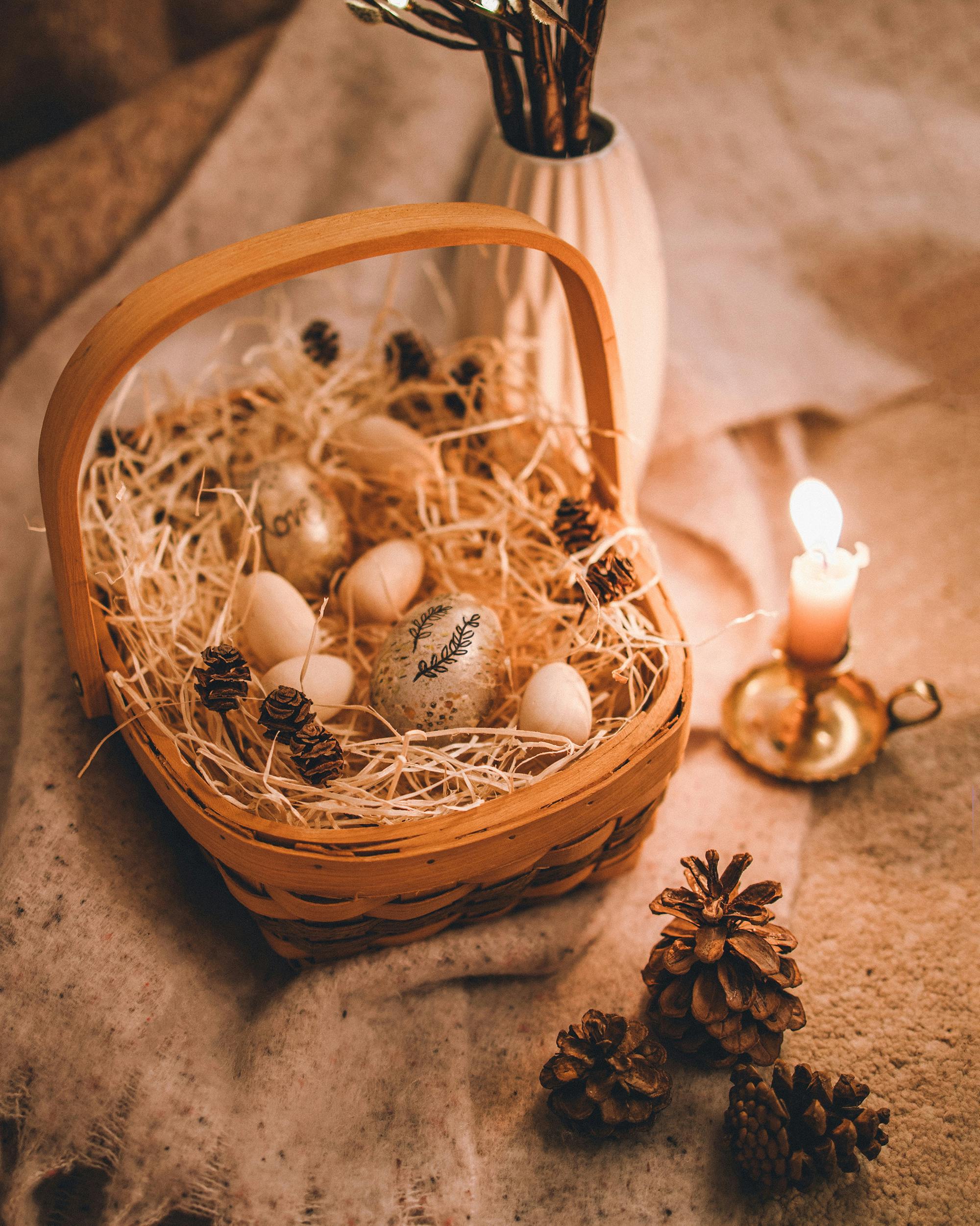 Cozy Easter basket decor featuring painted eggs and pinecones by candlelight.