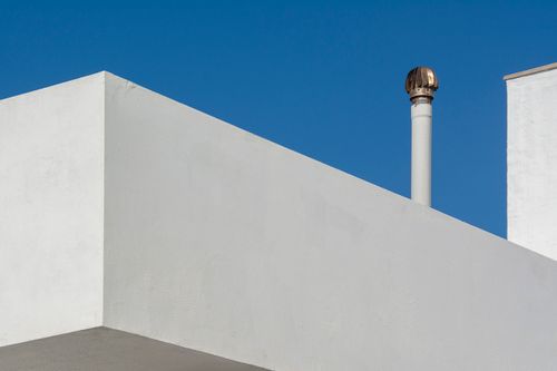 Free Minimalist architecture featuring white walls and chimney against a clear blue sky. Stock Photo