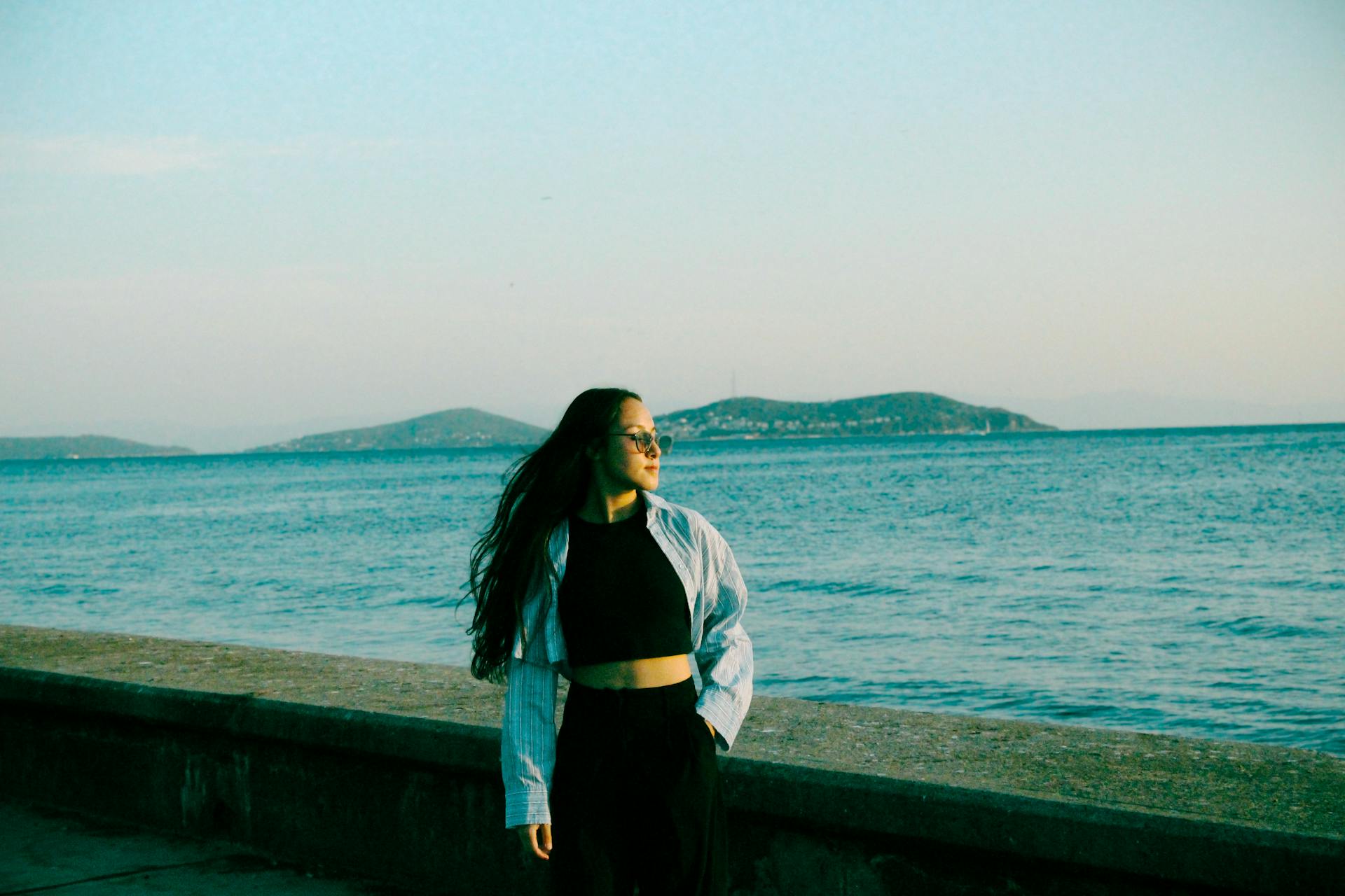 Young woman in sunglasses enjoying a peaceful moment by the sea in İstanbul. Perfect for travel and lifestyle themes.