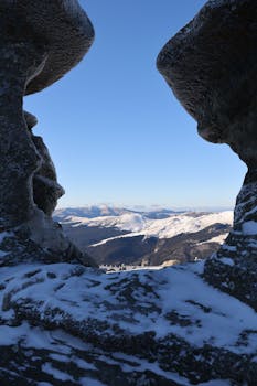 A breathtaking winter scene from Bucegi Mountains, Romania, showcasing snow-capped peaks through rock formations.