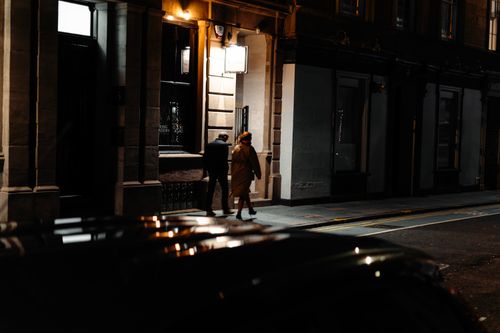 Free Candid night scene of two adults walking on a street in Edinburgh, Scotland. Stock Photo