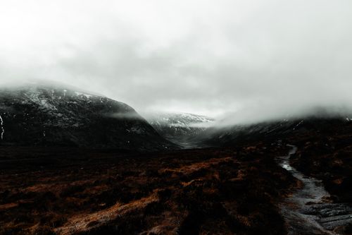 Free Majestic view of the misty Scottish Highlands with moody skies and rugged terrain. Stock Photo