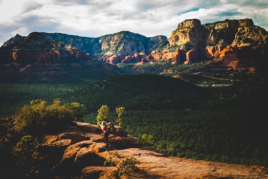 Woman performing yoga pose on a rocky ledge against the stunning Sedona landscape during sunset.