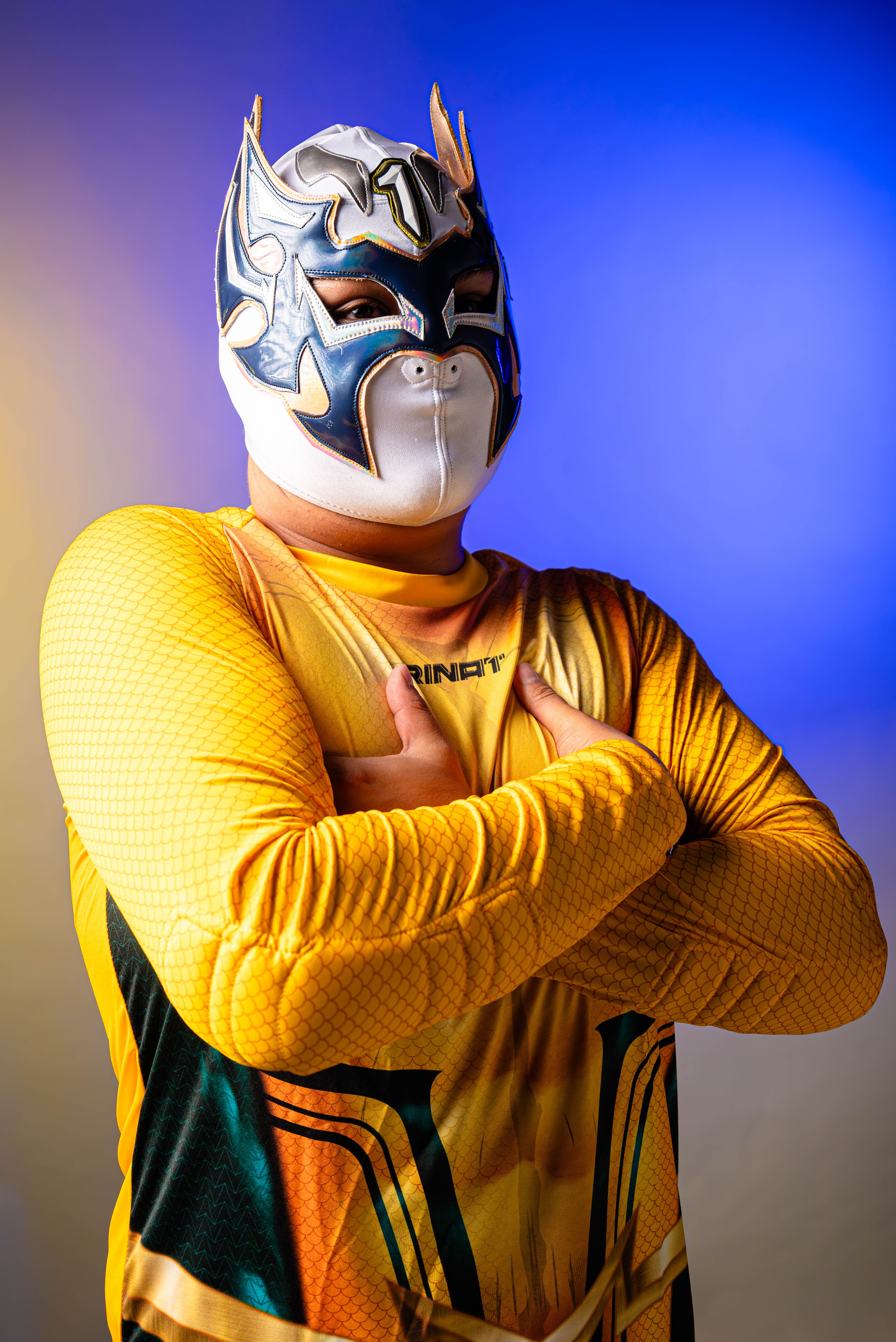 Vibrant luchador in traditional mask and costume, posing with arms crossed.